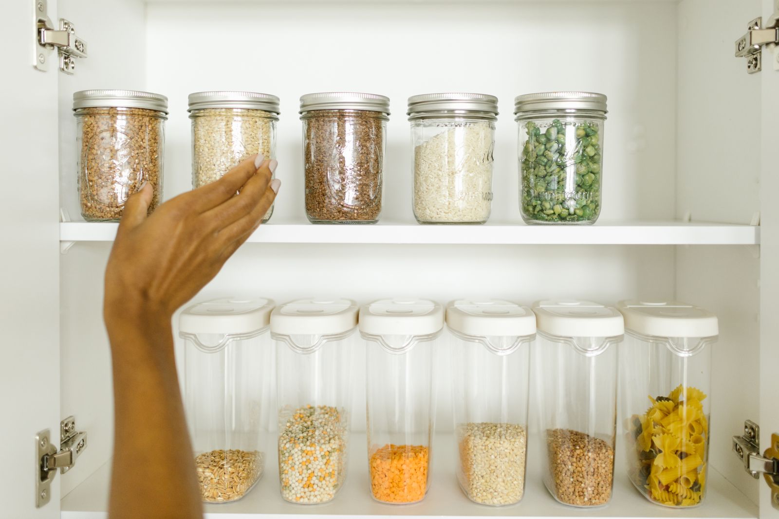 A hand selecting dry grains from a real pantry shelf